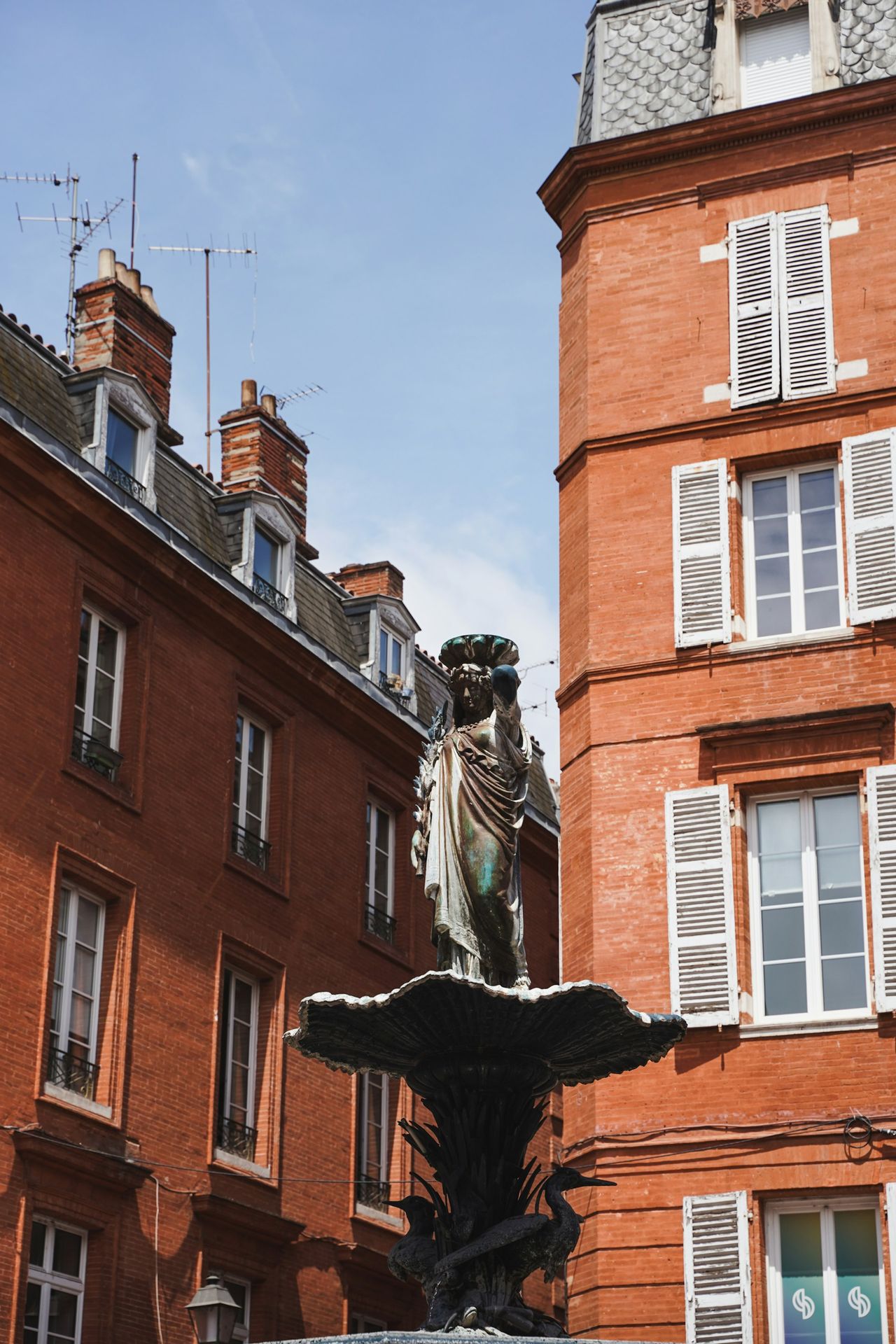 A fountain in front of a red brick building